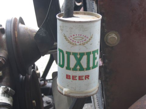 1996 Ford Bronco - A Dixie Beer can is affixed to the engine of a vehicle, possibly as a makeshift container.