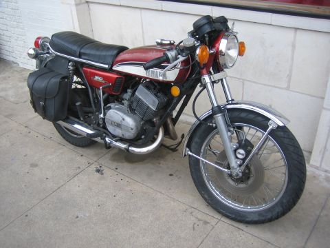 1996 Ford Bronco - A vintage Yamaha motorcycle with saddlebags is parked on a sidewalk next to a building.