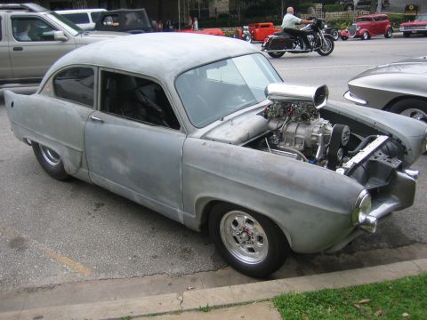 1996 Ford Bronco - A heavily modified car with a supercharger is seen on the street, with other vehicles in the background.