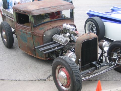 1996 Ford Bronco - A heavily customized and weathered pickup truck is displayed outdoors, its V8 engine and unique exhaust system.
