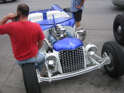 1996 Ford Bronco - A man sits on the tire of a custom hot rod while talking on a phone.