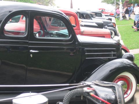 1996 Ford Bronco - A row of vintage cars, including a black coupe, are displayed outdoors on a grassy area.