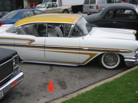 1996 Ford Bronco - A classic 1958 Chevrolet Impala, distinguished by its two-tone paint and gold accents, parked curbside.