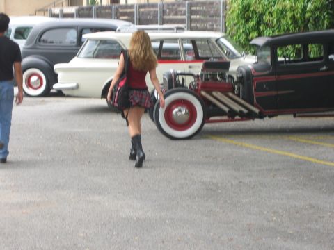 1996 Ford Bronco - A hot rod is parked next to other vehicles, with a woman walking away from the camera.