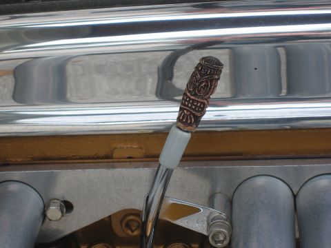 1996 Ford Bronco - Close-up of a custom tiki shift knob on a vehicle's carburetor linkage.