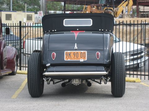 1996 Ford Bronco - The rear view of a black hot rod shows its wide tires and custom exhaust system.
