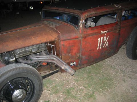 1996 Ford Bronco - A heavily rusted rat rod with a custom exhaust and racing numbers is parked outdoors.