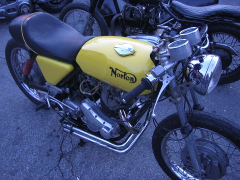 1996 Ford Bronco - A yellow Norton motorcycle is parked next to another motorcycle on a cracked asphalt surface.