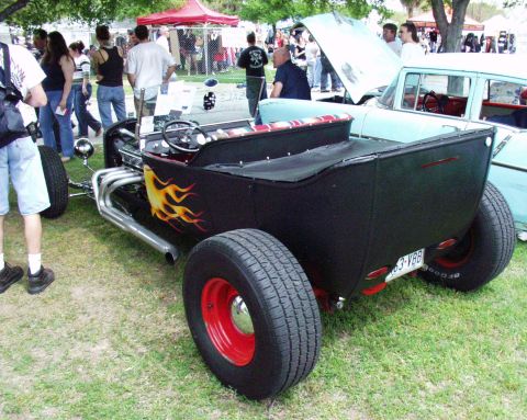 1996 Ford Bronco - A black hot rod with flame decals and red wheels is displayed outdoors next to another vehicle.