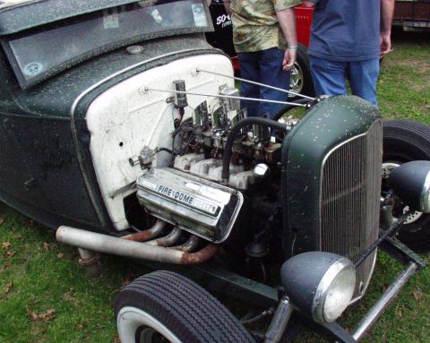 1996 Ford Bronco - A custom hot rod with a prominent V8 engine is displayed outdoors, with two onlookers in the background.