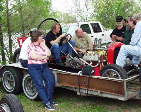 1996 Ford Bronco - A group of people examine a custom hot rod with a prominent engine, loaded onto a trailer.