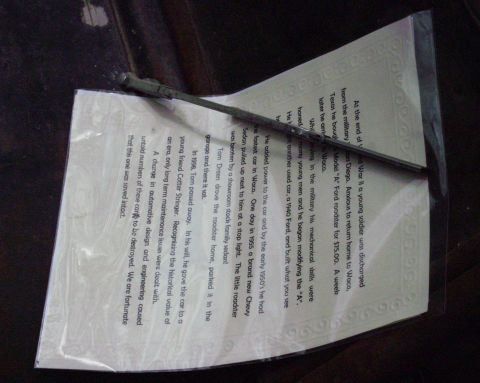 1996 Ford Bronco - A document detailing a car's history lies on a dark surface with a wiper blade resting on it.