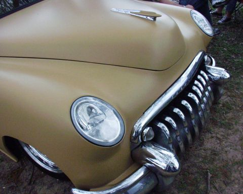 1996 Ford Bronco - A tan car's front grille and headlights are visible in this close-up shot.
