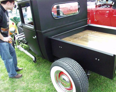 1996 Ford Bronco - A custom black hot rod pickup truck is displayed outdoors with other vehicles in the background.