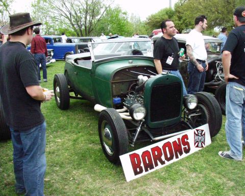 1996 Ford Bronco - A green hot rod is displayed with a club sign, surrounded by spectators and other vehicles.