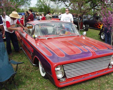1996 Ford Bronco - Customized classic car with flame paint and chrome grille is displayed at an outdoor car show.