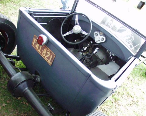 1996 Ford Bronco - The interior of a vintage hot rod is visible, a steering wheel, dashboard, and a side-mounted license plate.