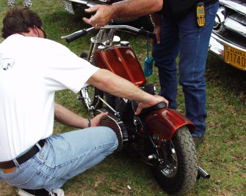1996 Ford Bronco - Two men inspect a custom motorcycle with a metallic red finish.