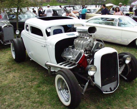 1996 Ford Bronco - A white hot rod with a prominent supercharger and sunroof is displayed outdoors among other vehicles.