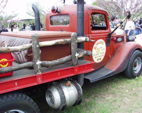 1996 Ford Bronco - This custom red flatbed truck features a prominent exhaust stack and rustic wooden bed railings.
