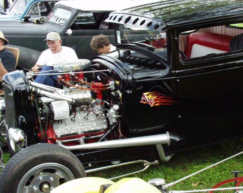 1996 Ford Bronco - A black hot rod with a powerful engine and custom flames is parked on grass.