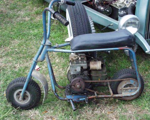 1996 Ford Bronco - A blue mini bike with a visible engine and chain drive sits on grass next to another vehicle.