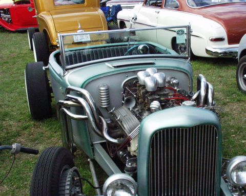 1996 Ford Bronco - A custom hot rod with a prominent V8 engine and multiple carburetors is displayed outdoors among other classic vehicles.