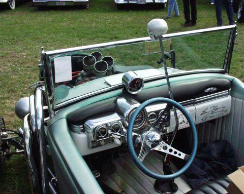 1996 Ford Bronco - The interior of a custom hot rod features a skull-topped shifter and a bright blue steering wheel, with other vehicles visible in the backg…