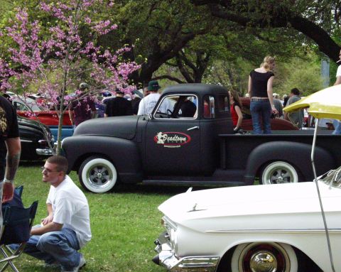 1996 Ford Bronco - A black pickup truck is parked on grass with people around it and a flowering tree.
