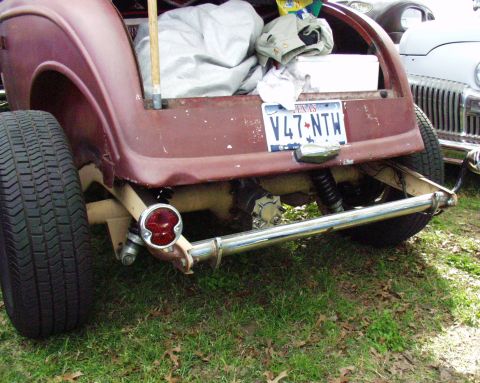 1996 Ford Bronco - The rear of a custom vehicle shows a Texas license plate and suspension components, with another car in the background.