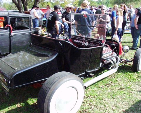 1996 Ford Bronco - A black hot rod with a custom build is displayed outdoors among spectators.