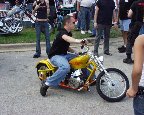 1996 Ford Bronco - A man rides a yellow custom motorcycle with chrome accents while onlookers stand nearby.