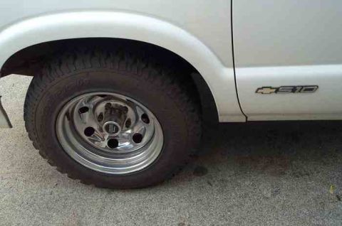 1988 Ford Bronco - A white pickup truck's side is shown, a chrome wheel and an "S10" badge.
