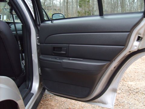 2004 Ford Crown Victoria - Interior view of a car's open rear door, revealing the black door panel and seat upholstery.