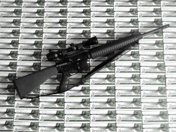Rifle with scope resting on boxes of Remington ammunition