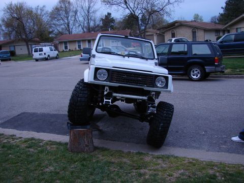 1990 Suzuki Samurai - Suzuki Samurai lifted for off-road use, front wheel angled.