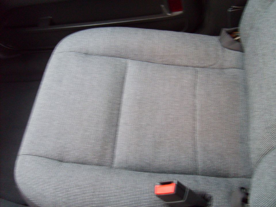 Gray fabric car seat with a red seatbelt buckle visible