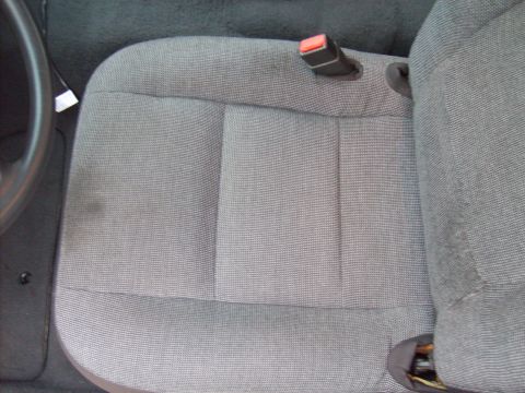 2004 Ford Crown Victoria - Interior view of a car seat with a visible seatbelt and part of the steering wheel.