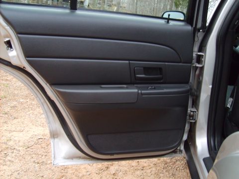 2004 Ford Crown Victoria - Interior view of a car's door panel, showing black plastic trim and a door handle.