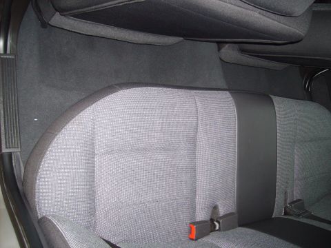 2004 Ford Crown Victoria - The rear interior of a vehicle shows gray fabric seats with black trim and seatbelt buckles visible.