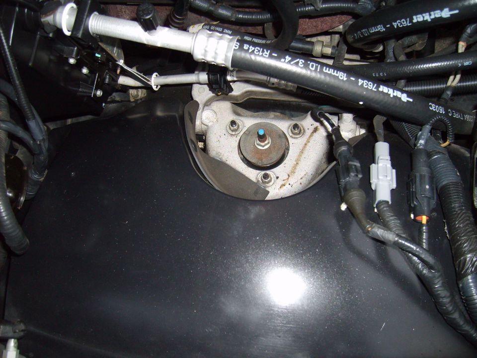 Engine bay detail with A/C hoses, wiring connectors, and a bolted metal component