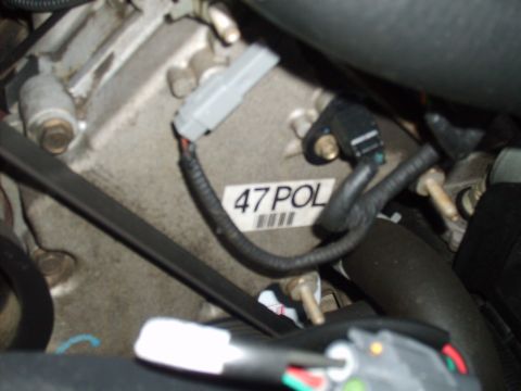 2004 Ford Crown Victoria - Close-up of an engine component with a label and electrical connectors visible.