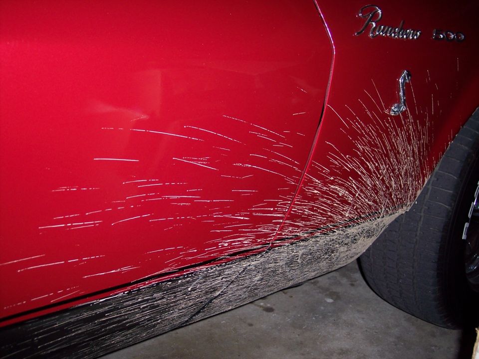 Mud spray on the red lower body of a Ranchero 500 with script and cobra emblems