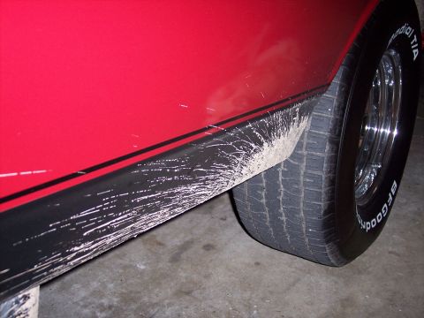 1972 Ford Ranchero - Mud splatters cover the black stripe and lower body panel of a red vehicle next-gen vehicle.