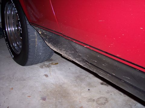 1972 Ford Ranchero - Side view of a red car's lower body panel and tire, showing dirt accumulation.