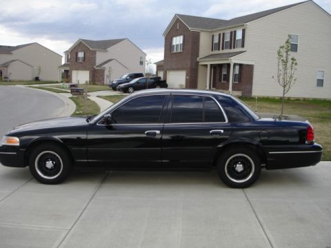 2001 Ford Crown Victoria - A black 2001 Ford Crown Victoria is parked on a suburban driveway with houses in the background.