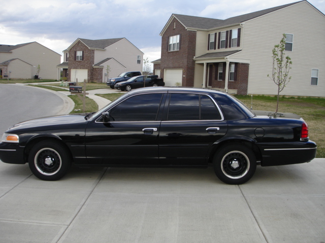 Black 2001 Ford Crown Victoria sedan parked on a driveway, side view