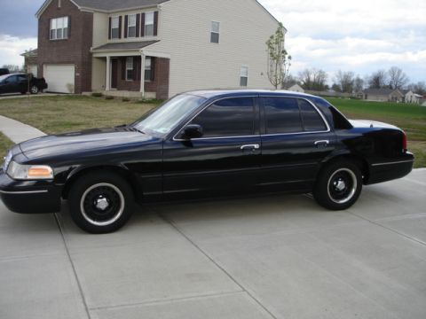 2001 Ford Crown Victoria - Side profile of a black 2001 Ford Crown Victoria sedan parked on a driveway.
