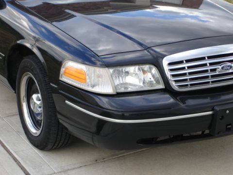 2001 Ford Crown Victoria - Front view of a black 2001 Ford Crown Victoria, showing the grille, headlights, and part of the front fender and wheel.