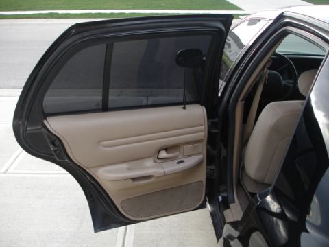 2001 Ford Crown Victoria - The interior of a black Ford Crown Victoria is shown with the passenger door open, revealing tan upholstery.